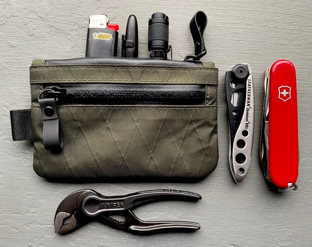 Miniature everyday carry tools stored in a technical fabric zip pouch for EDC.